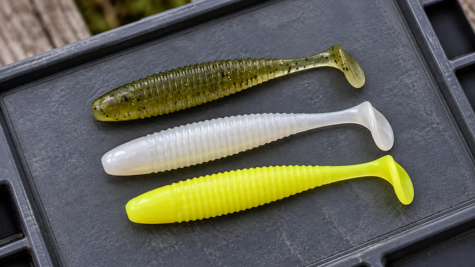 Drei unmontierte Gummifische in Oliv, Weiß und Gelb.